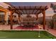 Outdoor dining under a grand pergola, with putting green, a barbecue, and meticulous landscaping enhance this outdoor oasis at 17541 W Statler Dr, Surprise, AZ 85388