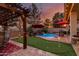Serene backyard featuring a pergola-covered dining area, putting green, and cozy pool, perfect for outdoor entertaining at 17541 W Statler Dr, Surprise, AZ 85388