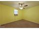 Cozy bedroom featuring bright yellow walls, carpet flooring, a ceiling fan, and natural light at 1763 W Pepper Pl, Mesa, AZ 85201