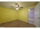 Sunny bedroom showcasing yellow walls, carpet, a ceiling fan, and an open doorway at 1763 W Pepper Pl, Mesa, AZ 85201