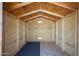 Interior view of a storage shed with wooden walls, rafters, and a partial floor covering at 1763 W Pepper Pl, Mesa, AZ 85201