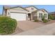 Beautiful home showcasing a brick driveway, a manicured lawn, and stone accents at 18324 W Highland Ave, Goodyear, AZ 85395