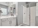 Bright primary bathroom showcasing a double vanity with quartz countertops and glass enclosed shower at 18324 W Highland Ave, Goodyear, AZ 85395