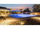 Inviting in-ground pool with a sun shelf, bistro table and desert landscaping with a sunset sky at 18324 W Highland Ave, Goodyear, AZ 85395