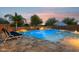 Inviting in-ground pool with a sun shelf, desert landscaping, lighting and colorful sunset sky at 18324 W Highland Ave, Goodyear, AZ 85395
