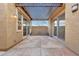 Covered patio featuring travertine pavers, decorative light fixtures, and backyard access through sliding doors at 29512 N 128Th Ln, Peoria, AZ 85383