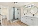Bright bathroom featuring double vanity, quartz countertop, framed mirrors, and glass shower with tile surround at 3021 N Randolph Rd, Phoenix, AZ 85014