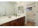 Bathroom with double sink vanity, wood cabinets, two mirrors, and wood-look tile floor at 3737 E Donald Dr, Phoenix, AZ 85050