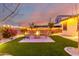 Cozy backyard featuring an inviting fire pit and well-manicured artificial grass, enhanced by ambient lighting for evening relaxation at 3739 S 180Th Dr, Goodyear, AZ 85338