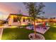Landscaped backyard featuring a fire pit, lush lawn, and ambient lighting for outdoor enjoyment at 3739 S 180Th Dr, Goodyear, AZ 85338