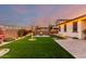 Enjoy this landscaped backyard with green artificial turf, a cozy fire pit, and string lights at 3739 S 180Th Dr, Goodyear, AZ 85338