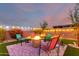 Beautiful backyard with a fire pit area, surrounded by lush green turf, paver patio, and colorful plants for entertaining at 3739 S 180Th Dr, Goodyear, AZ 85338