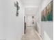 Clean, white hallway with tile flooring and decorative wall art leading to the front door at 3739 S 180Th Dr, Goodyear, AZ 85338