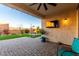 Inviting covered patio overlooking a beautifully landscaped backyard, complete with a television, grill, and artificial turf at 3739 S 180Th Dr, Goodyear, AZ 85338