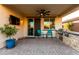 Outdoor patio featuring built-in grill, TV, with comfortable seating overlooking a beautifully landscaped backyard with artificial turf at 3739 S 180Th Dr, Goodyear, AZ 85338