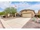 Tan single-story home featuring a two-car garage, desert landscaping, and a large driveway at 535 E Yellow Wood Ave, San Tan Valley, AZ 85140