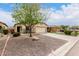 Tan single-story home featuring a two-car garage, desert landscaping, and a mature shade tree at 535 E Yellow Wood Ave, San Tan Valley, AZ 85140