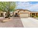 Tan single-story home featuring a two-car garage, desert landscaping, and a mature shade tree at 535 E Yellow Wood Ave, San Tan Valley, AZ 85140