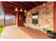 The covered outdoor patio features wood-look flooring, stone walls, and a ceiling fan at 535 E Yellow Wood Ave, San Tan Valley, AZ 85140
