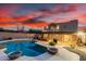 Backyard oasis featuring pool, covered patio, lush landscaping, and stunning twilight sky at 706 N Signal Butte Rd, Mesa, AZ 85207