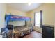 Bedroom features a bunkbed, laminate floors, neutral paint, a mini-fridge and a window at 7209 N Maple St, Maricopa, AZ 85139