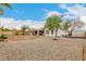 Wide view of the backyard with a white home, covered patio, and gravel and dirt ground at 923 E Aire Libre Ave, Phoenix, AZ 85022