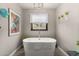 Bright bathroom with modern soaking tub next to a window with hanging plants at 923 E Aire Libre Ave, Phoenix, AZ 85022