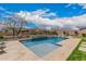 Inviting pool with a tanning ledge, water feature, travertine tile, and lush landscaping at 10717 E Tarragon Ave, Mesa, AZ 85212