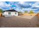 Wide backyard view of a white brick house, gravel yard and a tall wooden fence for privacy at 10947 W Mohave St, Avondale, AZ 85323