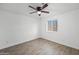 Bright bedroom features wood-look tile floors, white walls, ceiling fan, and natural light from a window at 10947 W Mohave St, Avondale, AZ 85323