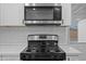 Close up of a modern stainless steel stove and microwave with white cabinets and tile backsplash at 10947 W Mohave St, Avondale, AZ 85323