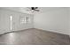 Open living room with a ceiling fan, gray wood-look flooring, and a glass panel door at 10947 W Mohave St, Avondale, AZ 85323