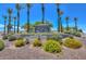 Welcoming entrance to Sun City West, beautifully landscaped with vibrant flowers and stately palm trees, creating a warm invitation at 13423 W Countryside Dr, Sun City West, AZ 85375