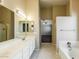 Bathroom with a large white vanity, large mirror, shower, and a peek into the spacious main bedroom at 1406 W Charleston Ave, Phoenix, AZ 85023