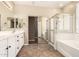 Elegant bathroom with dual vanity, soaking tub, glass-enclosed shower, and mirrored closet doors at 14686 W Clarendon Ave, Goodyear, AZ 85395