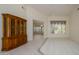 Spacious living room with neutral carpeting, tile accents, a ceiling fan, and a large window overlooking the yard at 15750 W Linksview Dr, Surprise, AZ 85374