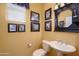 Charming powder room with a pedestal sink, decorative mirror, and tasteful wall art at 20562 N Bear Canyon Ct, Surprise, AZ 85387