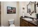 Powder room features a dark countertop, decorative mirror, and modern fixtures at 34463 N 99Th Way, Scottsdale, AZ 85262