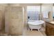 Bathroom with freestanding tub, glass block window, and neutral tile at 34463 N 99Th Way, Scottsdale, AZ 85262