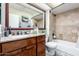 Bathroom featuring a wood vanity, framed mirror, and a tiled tub-shower combination, complete with fixtures at 3535 W Monte Cristo Ave # 115, Phoenix, AZ 85053