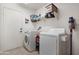 Bright laundry room features a modern washer, dryer, shelving, and tiled flooring at 40142 W Coltin Way, Maricopa, AZ 85138