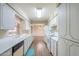 Galley kitchen showcases white cabinetry, appliances, and laminate flooring, open to the dining room at 4126 E Carmel Ave, Mesa, AZ 85206