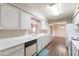 Spacious galley kitchen with white cabinets and appliances, adjacent to dining area, offers plenty of space at 4126 E Carmel Ave, Mesa, AZ 85206