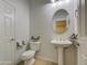 Half bathroom featuring a pedestal sink, modern fixtures and a decorative round mirror at 6192 S Claiborne Ave, Gilbert, AZ 85298