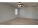 Bright bedroom with carpet, a ceiling fan, and a window; adjacent to a door leading to another room at 6192 S Claiborne Ave, Gilbert, AZ 85298