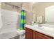 Clean bathroom featuring a single sink vanity, white tiled shower and tub combo with a colorful curtain at 7421 W Montgomery Rd, Peoria, AZ 85383