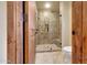 Modern bathroom with a frameless glass shower, marble tile, and wooden door at 10561 E Addy Way, Scottsdale, AZ 85262