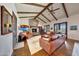 Spacious living room boasts exposed wood beams, a stone fireplace, wood floors, and plenty of seating with a piano at 10561 E Addy Way, Scottsdale, AZ 85262