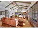 Beautiful living room featuring a stone fireplace, exposed wood beams, wood floors, leather seating, and piano at 10561 E Addy Way, Scottsdale, AZ 85262