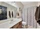 Bathroom with wood vanity, white sink, and shower with decorative patterned curtain at 10780 W Woodland Ave, Avondale, AZ 85323